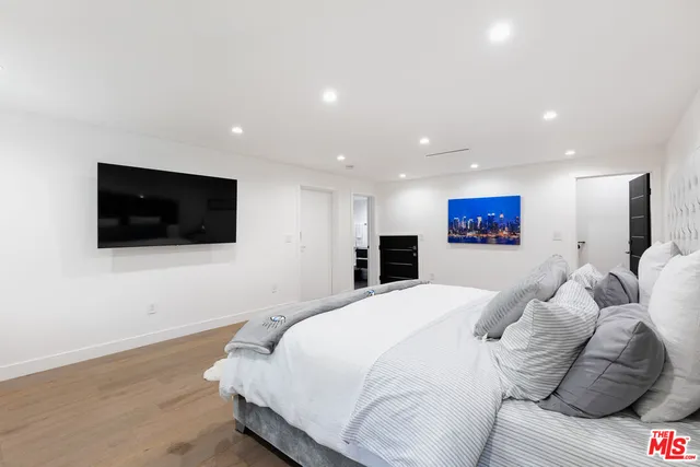 a spacious bedroom with a bed and a television