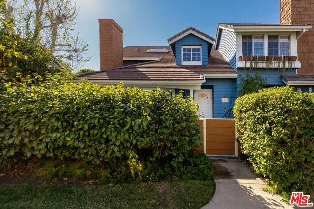 a view of a house with brick walls and a yard with plants