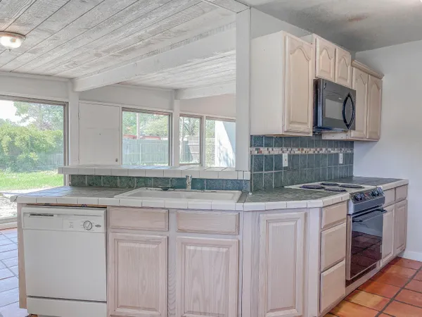 a kitchen with granite countertop a sink a stove and cabinets
