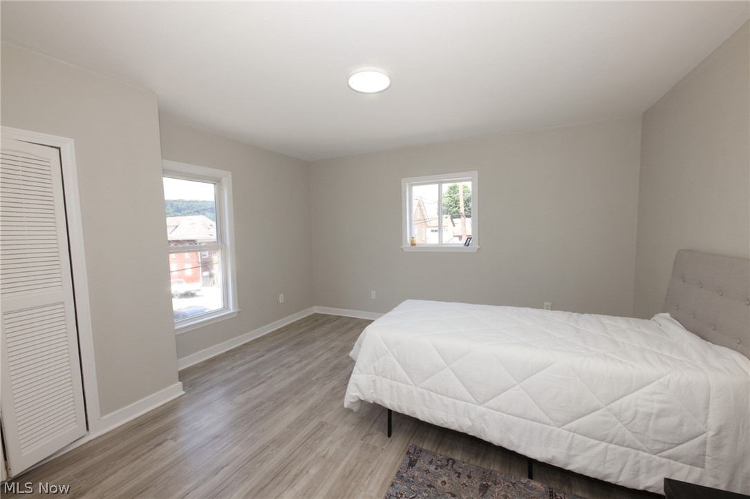 416 5th Street Chester, WV 26034 - Photo 19 of 24 Spacious room featuring light wood-finish flooring, neutral wall paint, two large windows, a ceiling-mounted light fixture, and a louvered bi-fold closet door