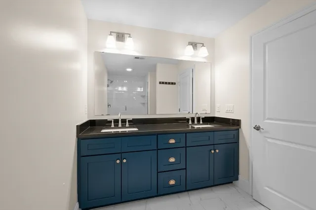 a bathroom with a granite countertop double vanity sink and mirror