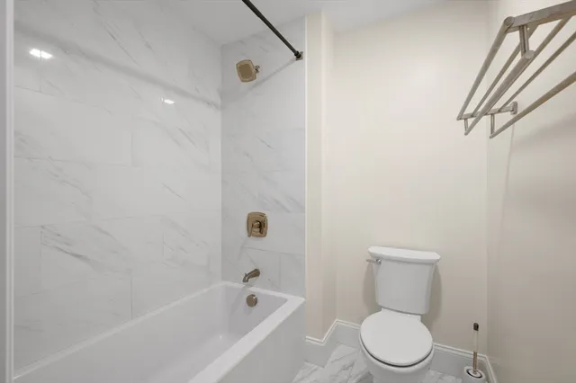 a white toilet sitting next to a bath tub