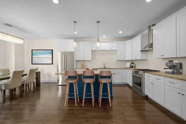 a large kitchen with stainless steel appliances granite countertop a dining table chairs and granite counter tops