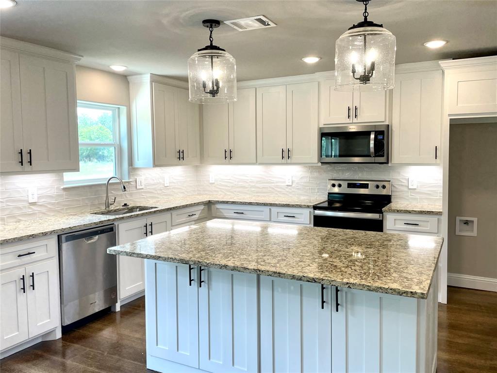 a kitchen with kitchen island granite countertop stainless steel appliances a stove a sink and a refrigerator