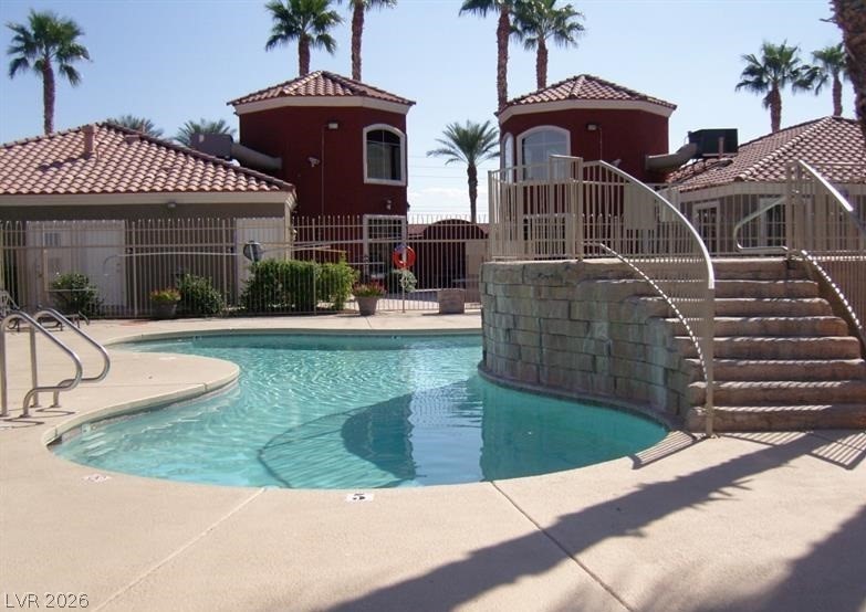 4730 East Craig Road, Unit 2102 Las Vegas, NV 89115 - Photo 6 of 13 Palm trees shade a refreshing pool, nestled among charming Mediterranean-inspired buildings.