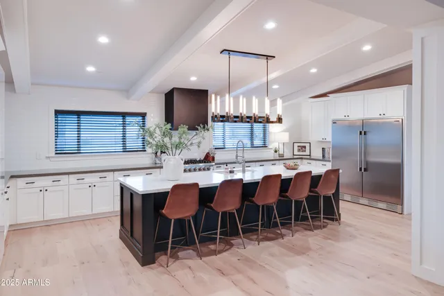 a kitchen with stainless steel appliances kitchen island granite countertop a table chairs sink and cabinets