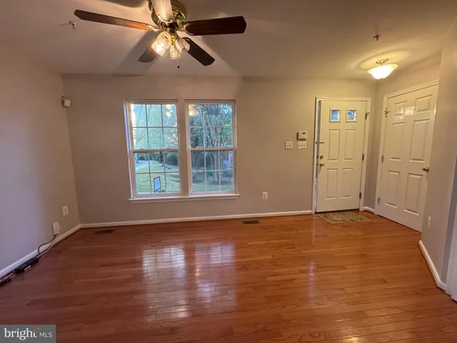 a view of an empty room with window and wooden floor