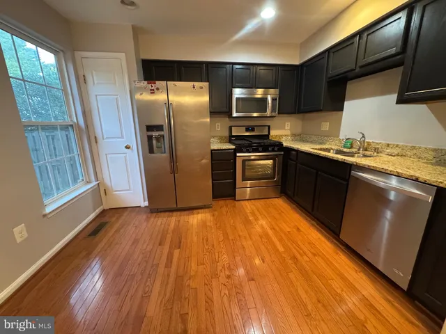 a kitchen with granite countertop stainless steel appliances a refrigerator microwave and sink