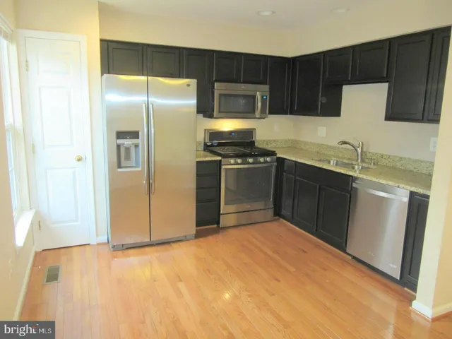 a kitchen with stainless steel appliances granite countertop a refrigerator and a sink
