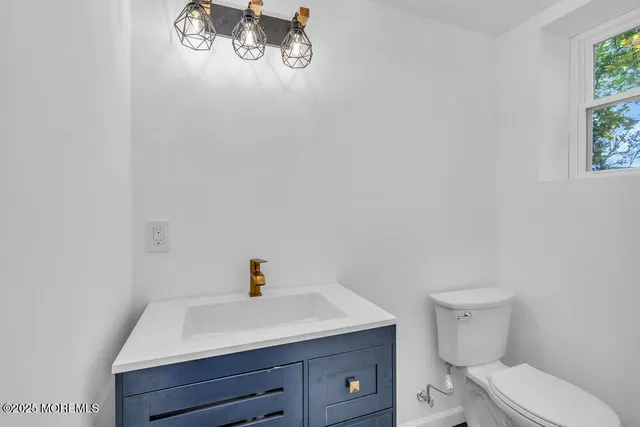 a bathroom with a toilet sink vanity and window