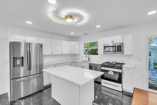 a kitchen with stainless steel appliances a refrigerator a stove a sink dishwasher and a refrigerator with wooden floor