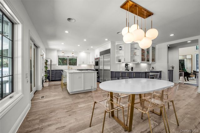 a large kitchen with a dining table wooden floor stainless steel appliances and cabinets
