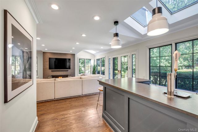 a large living room with stainless steel appliances granite countertop couches a flat screen tv and a sink