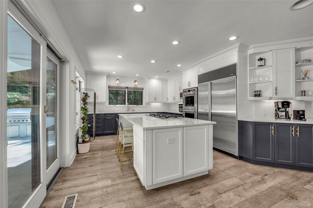 a kitchen with stainless steel appliances granite countertop a refrigerator a sink a stove and a refrigerator