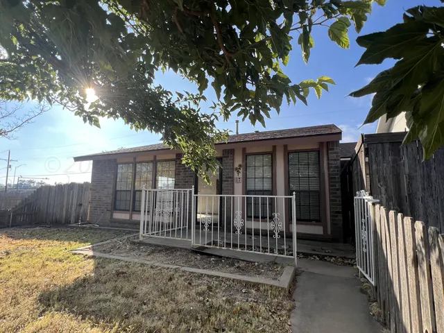 a view of a house with a small yard and wooden fence