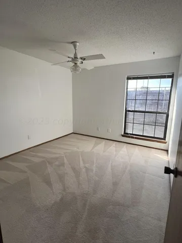 an empty room with windows and ceiling fan view