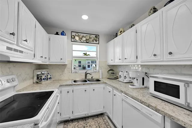 a kitchen with granite countertop a sink a stove and cabinets