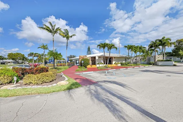 a view of a house with a big yard and palm trees