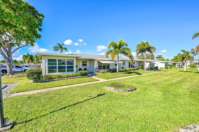 a view of a house with a big yard and large trees