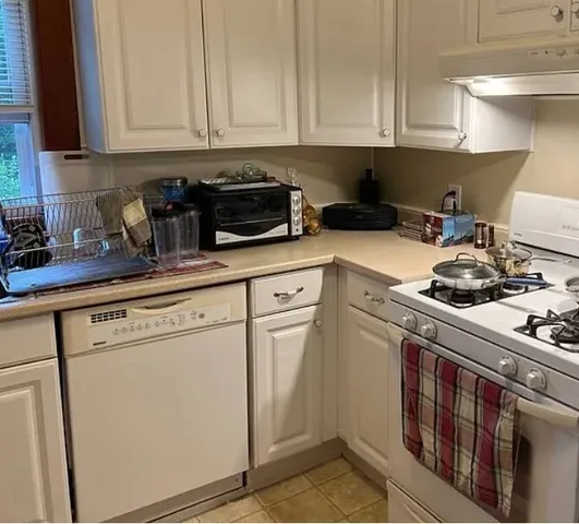 a kitchen with stainless steel appliances granite countertop a sink a stove and white cabinets