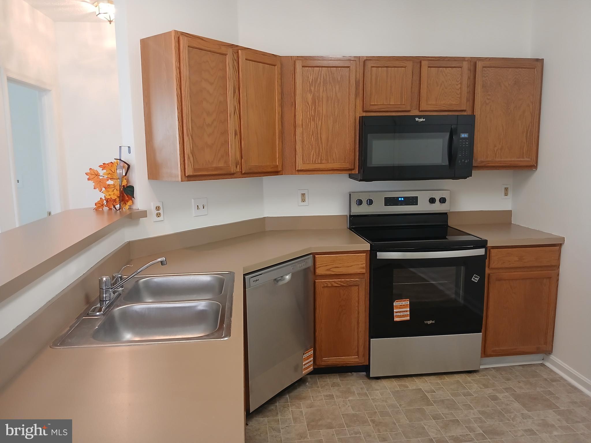 7201 Bogley Road, Unit 203 Windsor Mill, MD 21244 - Photo 9 of 21 a kitchen with stainless steel appliances a stove a microwave a sink and cabinets