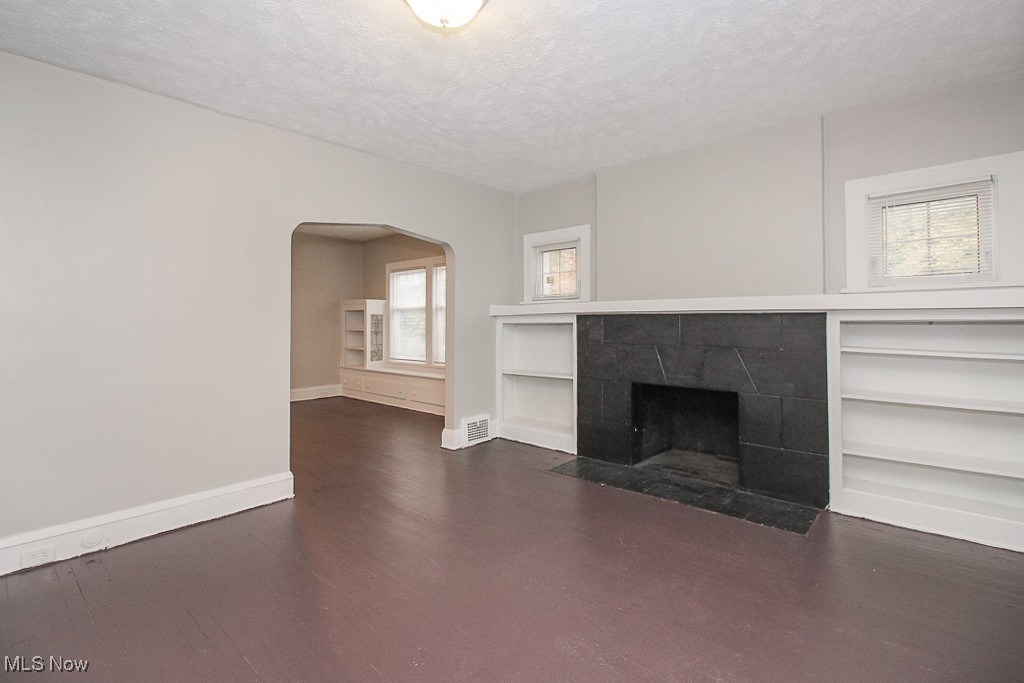 3085 Somerton Road Cleveland, OH 44118 - Photo 4 of 16 Unfurnished living room with visible vents, a textured ceiling, arched walkways, a fireplace, and baseboards