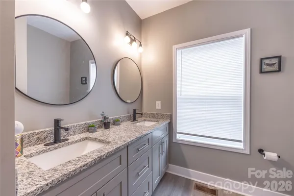 a bathroom with a granite countertop double vanity and a mirror