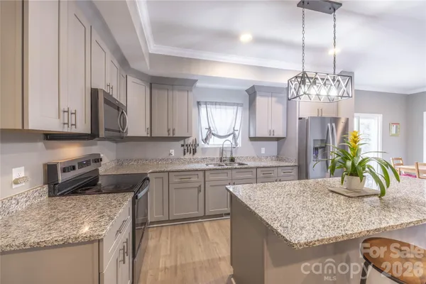 a kitchen with kitchen island granite countertop stainless steel appliances sink stove and cabinets