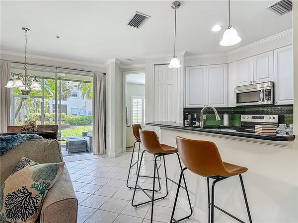 a kitchen with stainless steel appliances granite countertop a stove a refrigerator a kitchen island a dining table and chairs with the granite countertops