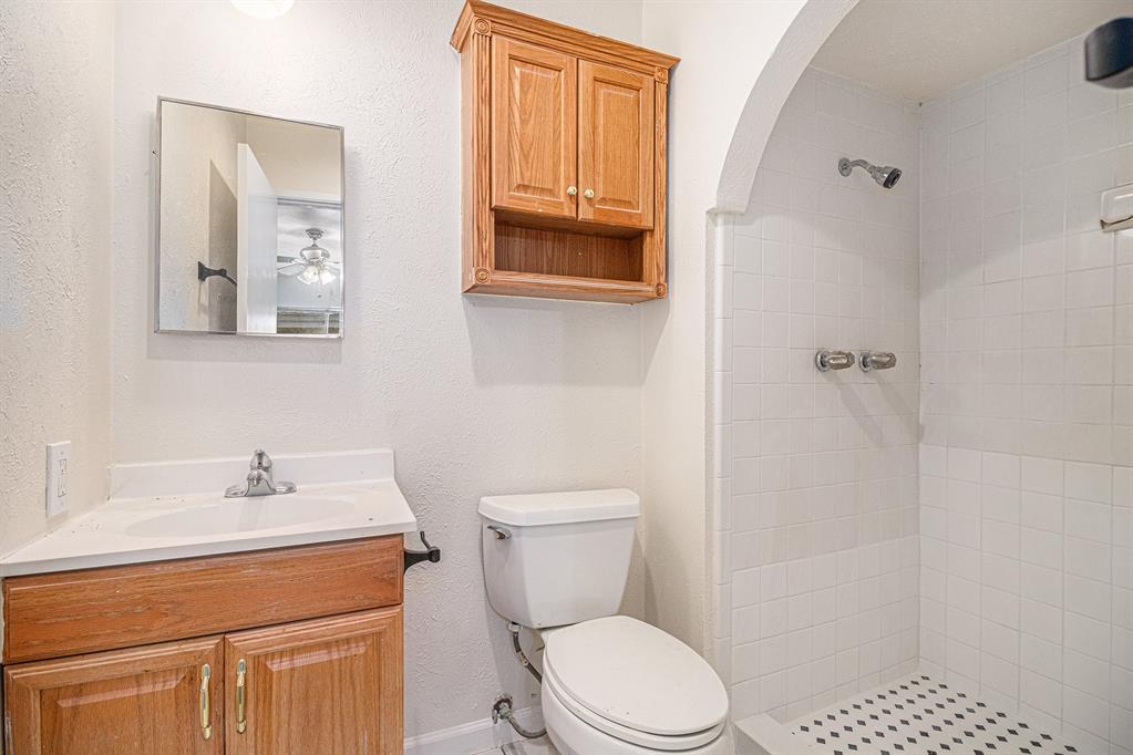 1814 Addington Drive Carrollton, TX 75007 - Photo 21 of 24 Bathroom featuring a tile shower, oversized vanity, ceiling fan, and toilet