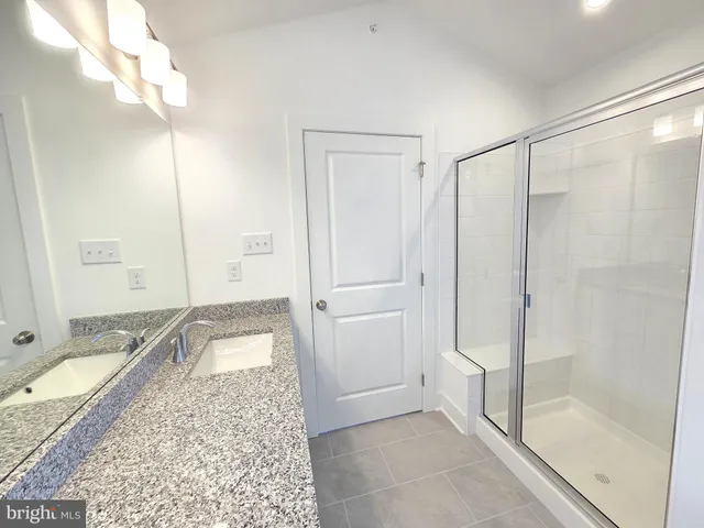 a bathroom with a granite countertop sink and shower
