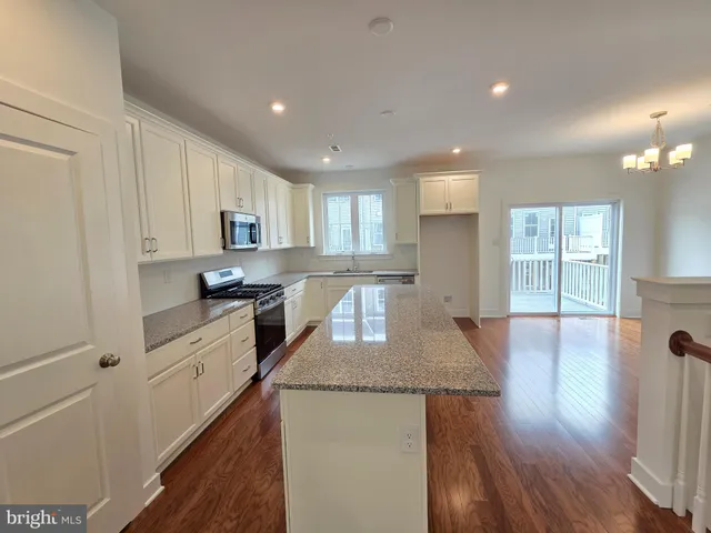 a kitchen with kitchen island granite countertop wooden floors and white cabinets