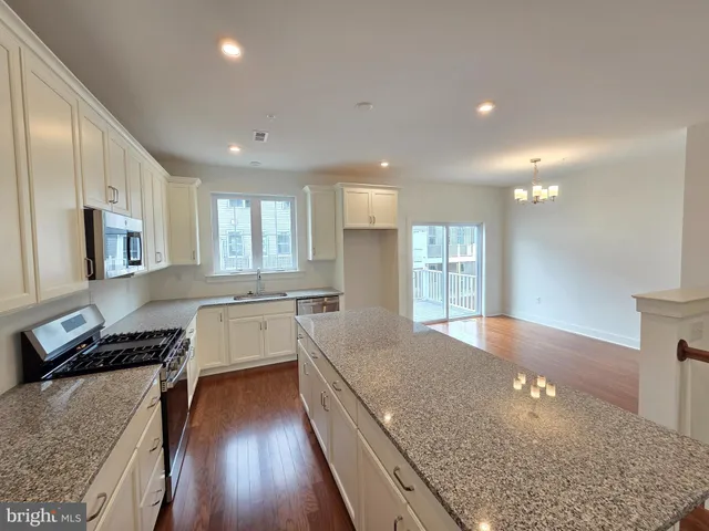 a large kitchen with stainless steel appliances granite countertop a lot of counter space and wooden floor