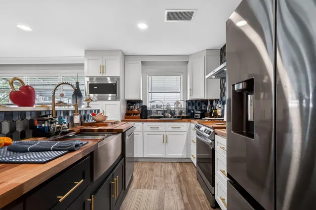 a kitchen with stainless steel appliances granite countertop a refrigerator a stove and white cabinets