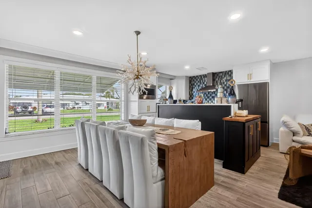 a living room with stainless steel appliances kitchen island granite countertop a refrigerator a sink a stove and a wooden floors