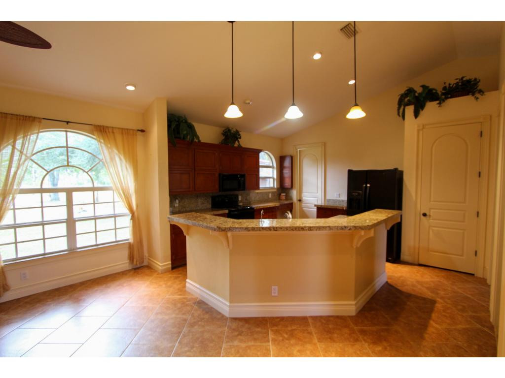 4125 13th Avenue Southwest Naples, FL 34116 - Photo 22 of 34 a living room with stainless steel appliances kitchen island granite countertop a living room a couch and a flat screen tv