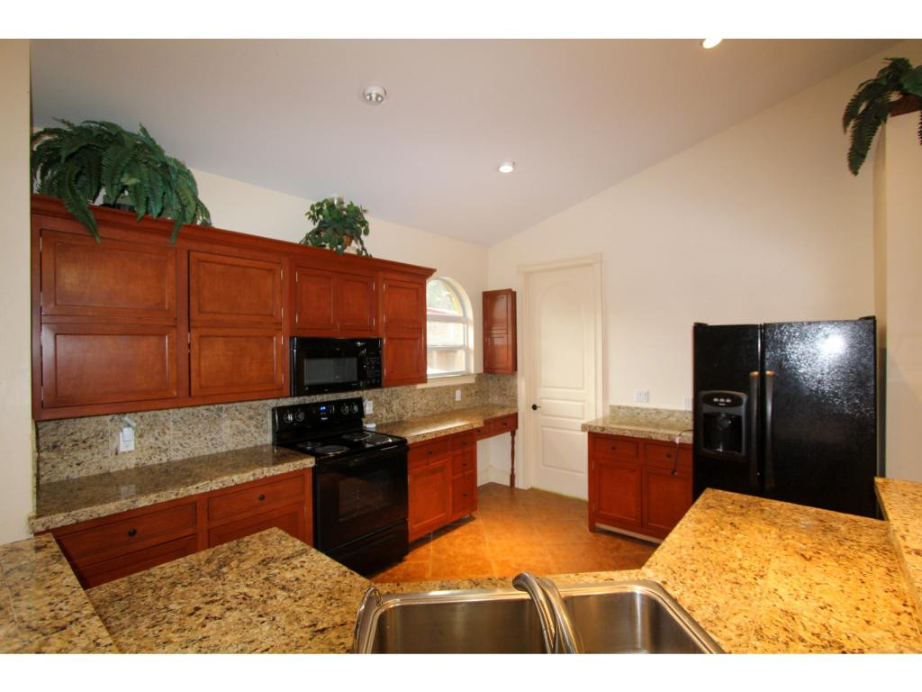 4125 13th Avenue Southwest Naples, FL 34116 - Photo 23 of 34 a kitchen with stainless steel appliances kitchen island granite countertop a refrigerator and a stove top oven