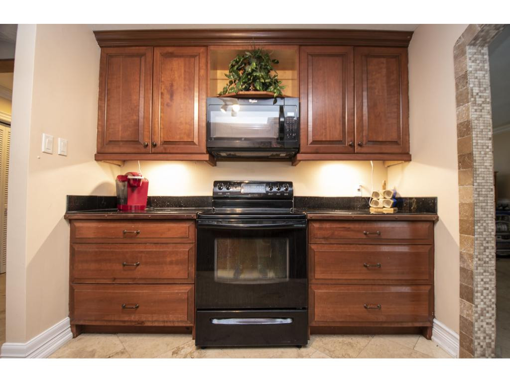 4125 13th Avenue Southwest Naples, FL 34116 - Photo 5 of 34 a kitchen with wooden cabinets and a stove top oven