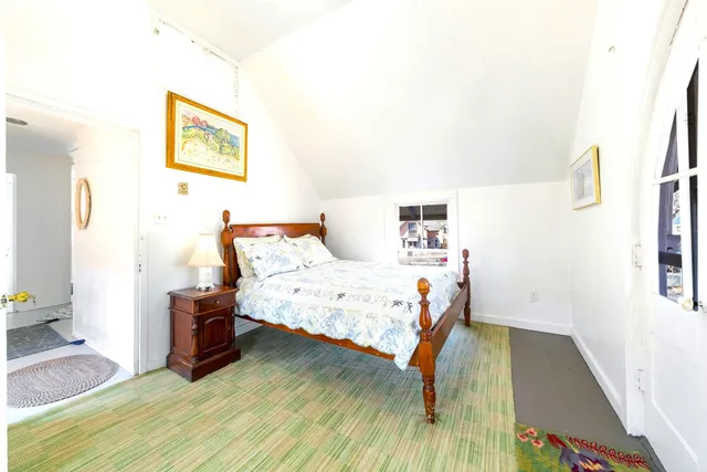 a bedroom with a bed wooden floor and a large window