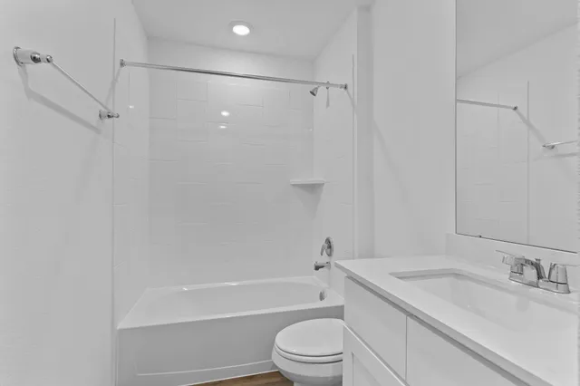 a bathroom with a granite countertop bathtub shower sink vanity and toilet