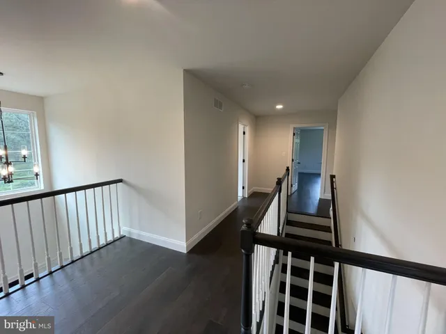 a view of a hallway with wooden floor and stairs