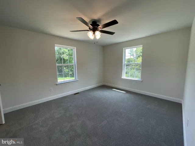 an empty room with a window and a ceiling fan