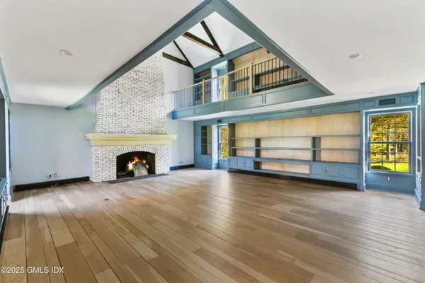 an empty room with wooden floor fireplace and windows