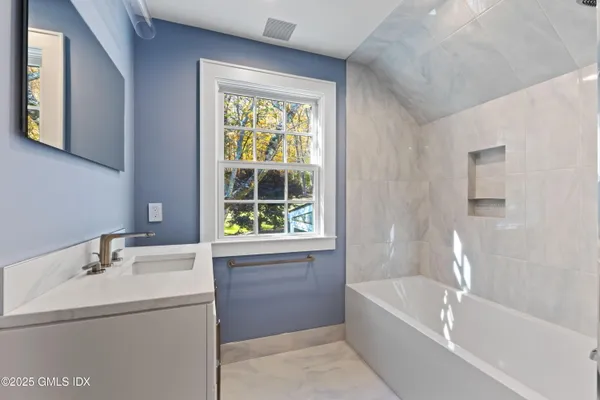 a bathroom with a bathtub sink and mirror