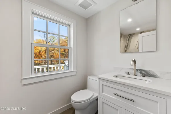 a bathroom with a toilet a sink a mirror and a window