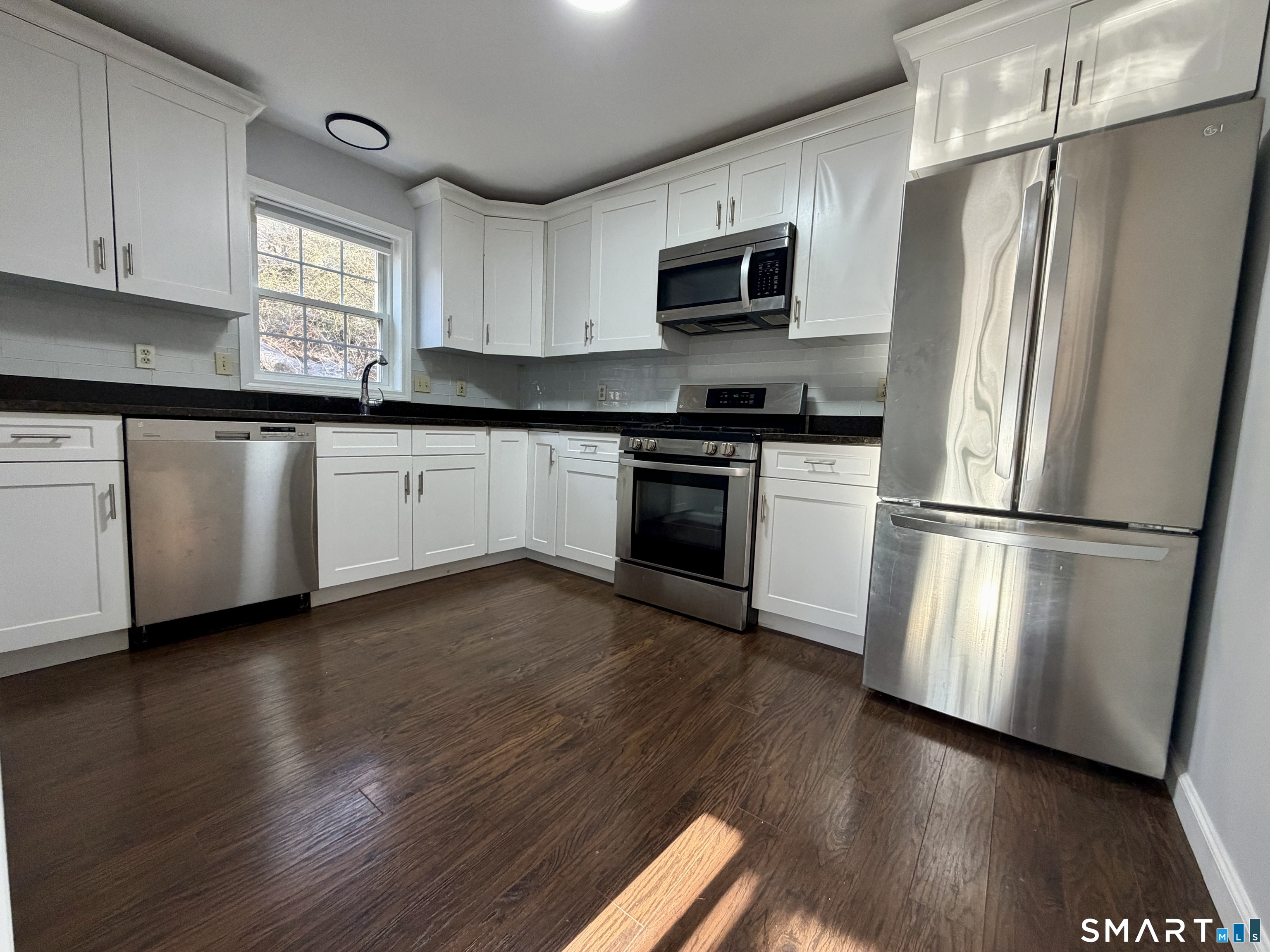 154 East Main Street, Unit A Branford, CT 06405 - Photo 2 of 17 a kitchen with granite countertop wooden floors stainless steel appliances and window