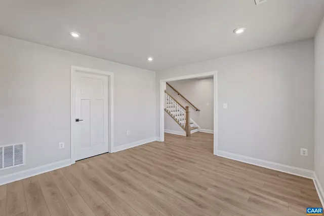 a large kitchen with stainless steel appliances kitchen island granite countertop a stove a sink a refrigerator and white cabinets with wooden floor