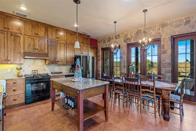 a kitchen with stainless steel appliances granite countertop a table chairs and a refrigerator