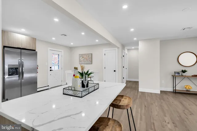 a room with stainless steel appliances kitchen island granite countertop furniture a refrigerator and wooden floor