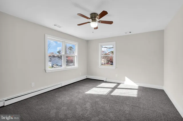 an empty room with windows and ceiling fan